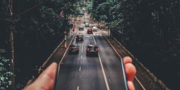 Person holding phone out of which a road appears